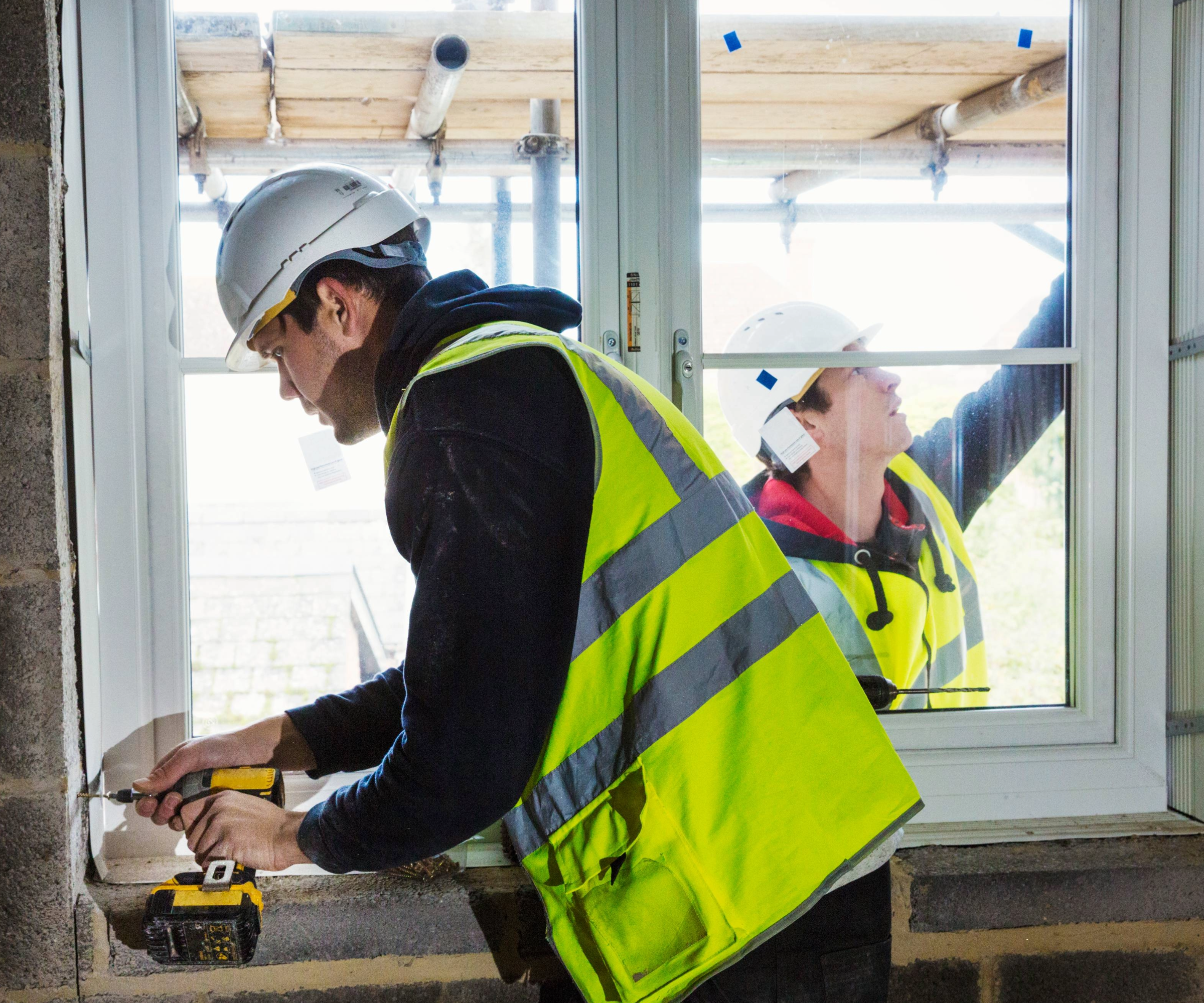 Two work people fitting a window