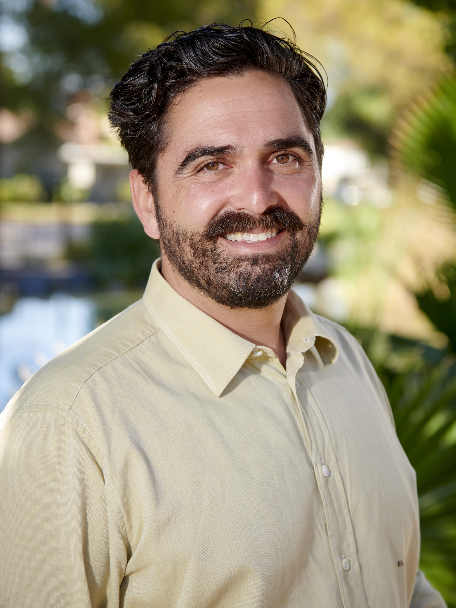 a white man in a light yellow shirt with brown hair and a beard