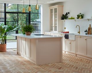A contemporary plaster pink kitchen with island and Herringbone Terracotta-colored floor tiles with brick effect