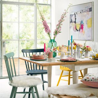 Wooden table surrounded by brightly painted dining chairs