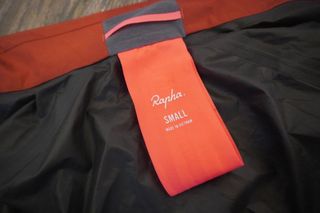 Image shows the pink tag for packing away the Rapha Brevet Gore-Tex Rain Jacket