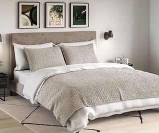 A white comforter on a bed with a gray throw.