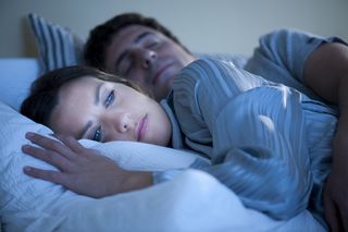 Couple in bed, woman awake