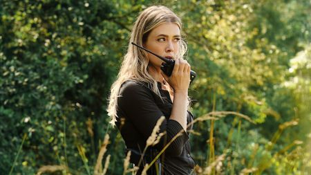 Melissa Roxburgh holds up a radio transceiver to her face in The Hunting Party on NBC. 