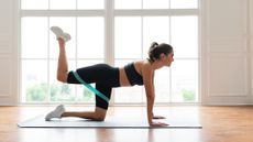 Woman doing a glute kickback with a resistance band on a yoga mat