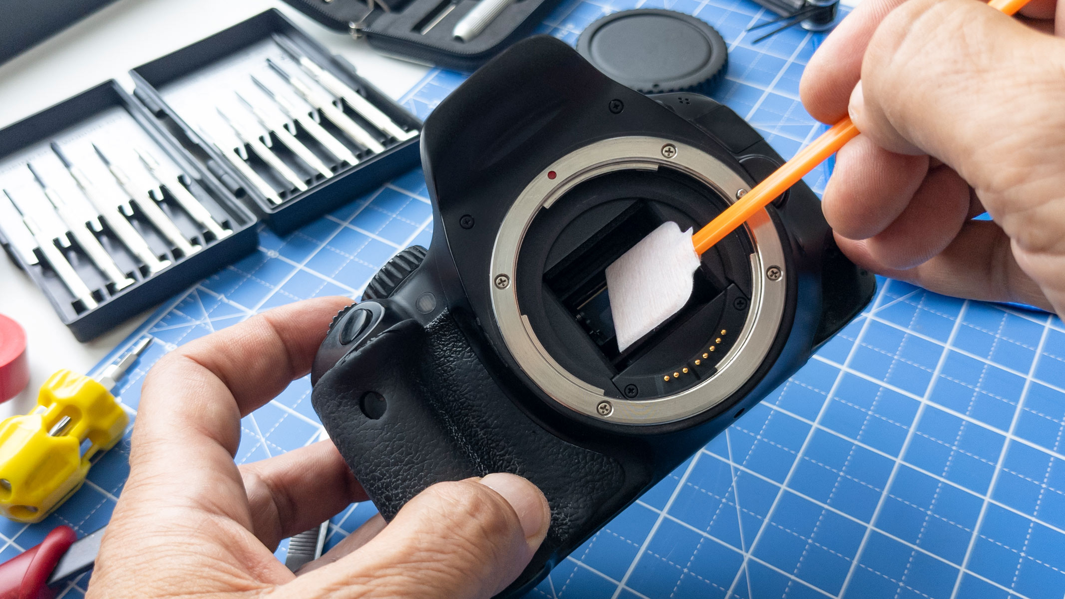 A person using a swab to clean a camera sensor.