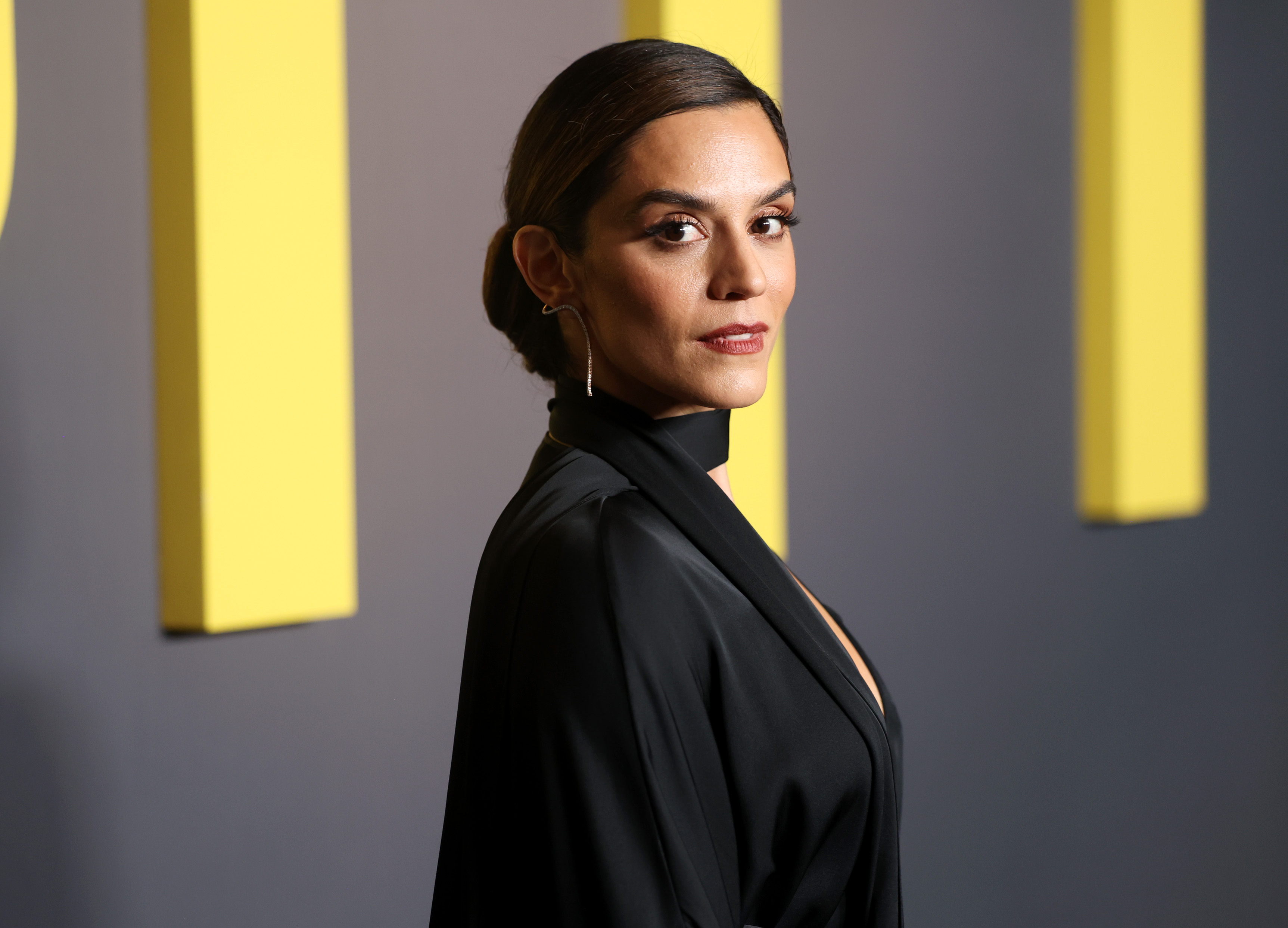 Sepideh Moafi looks over her shoulder and wars a black satin high neck gown while attending the Los Angeles Red Carpet Premiere of Max Original Drama Series THE PITT at DGA Theater Complex on January 07, 2026 in Los Angeles, California