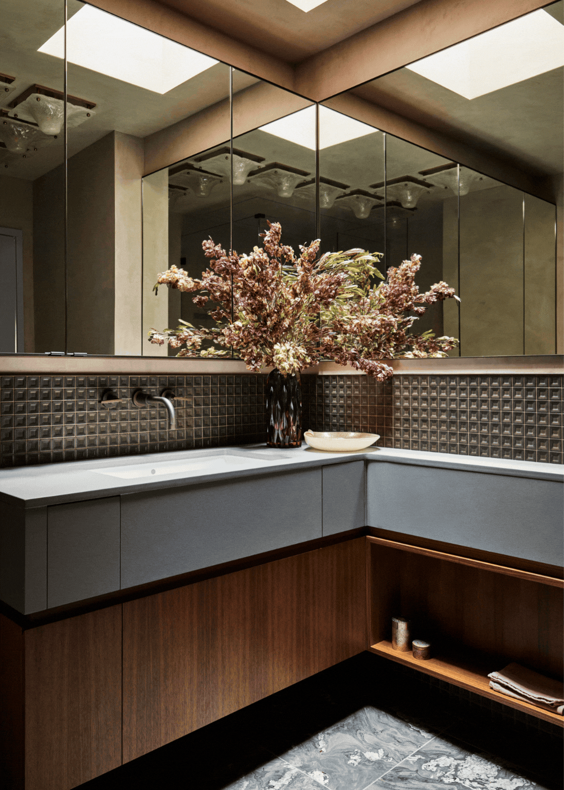 GIF of a modern bathroom with lots of different textures (wood, stone, tile, and mirrors) with the lights turning off and on.