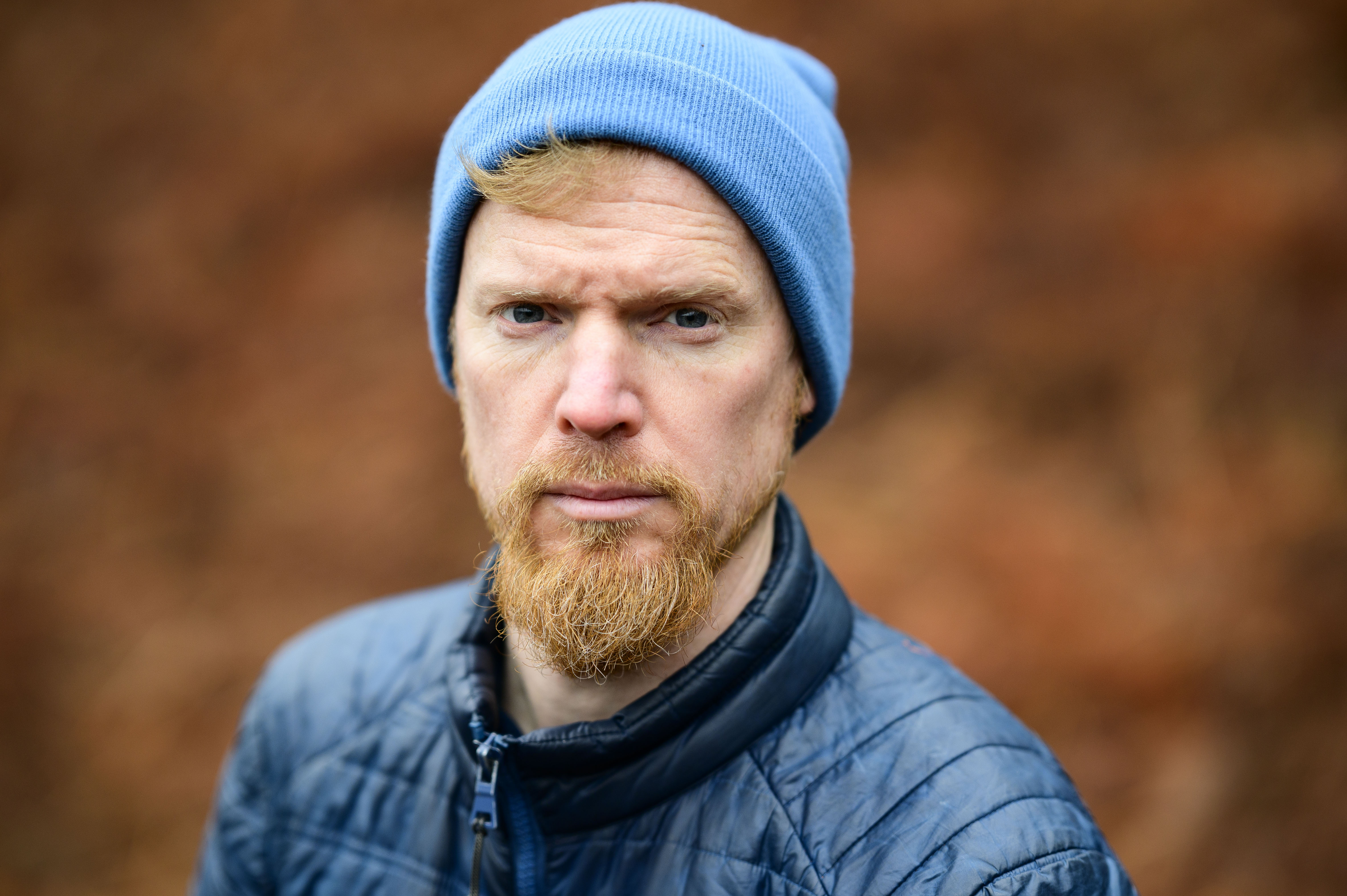 Viltrox AF 85mm F1.4 Pro lens sample gallery: man in a blue beanie, with blurry bronze-colored ferns in the background
