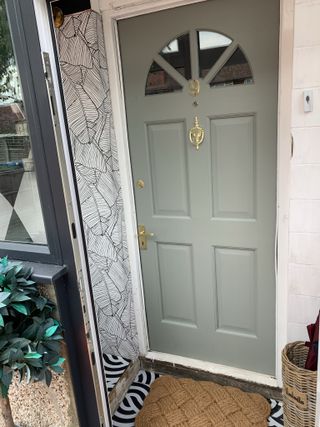Sage green front door in tiny decorated porch
