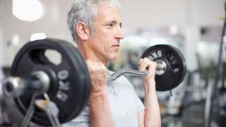 Older man lifting barbell to chest