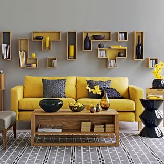 room with mustard yellow sofa and wooden table with shelves