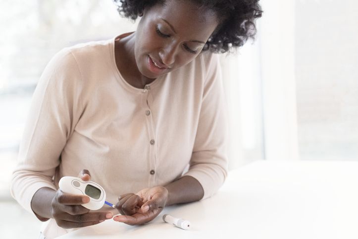 A woman measures her blood sugar using a blood glucose monitor.