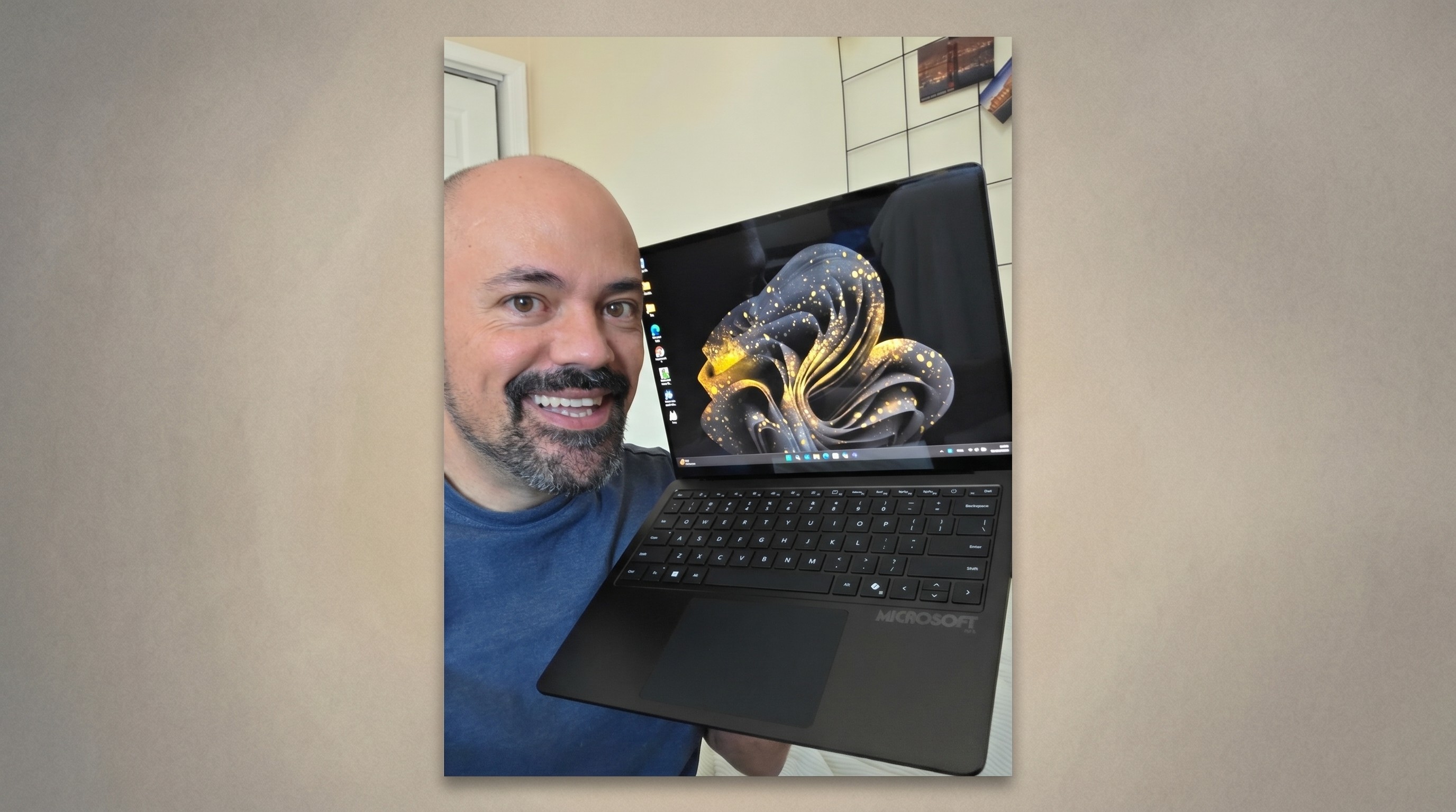 Rhener Furtado proudly holds a 50th Anniversary Surface Laptop featuring an elegant gold design, showcasing its stylish appearance.