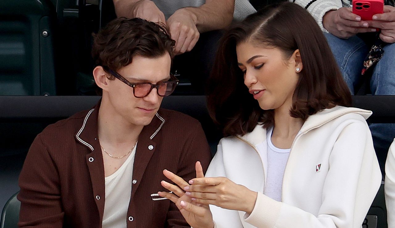 Zendaya and Tom Holland sitting together wearing coordinating outfits