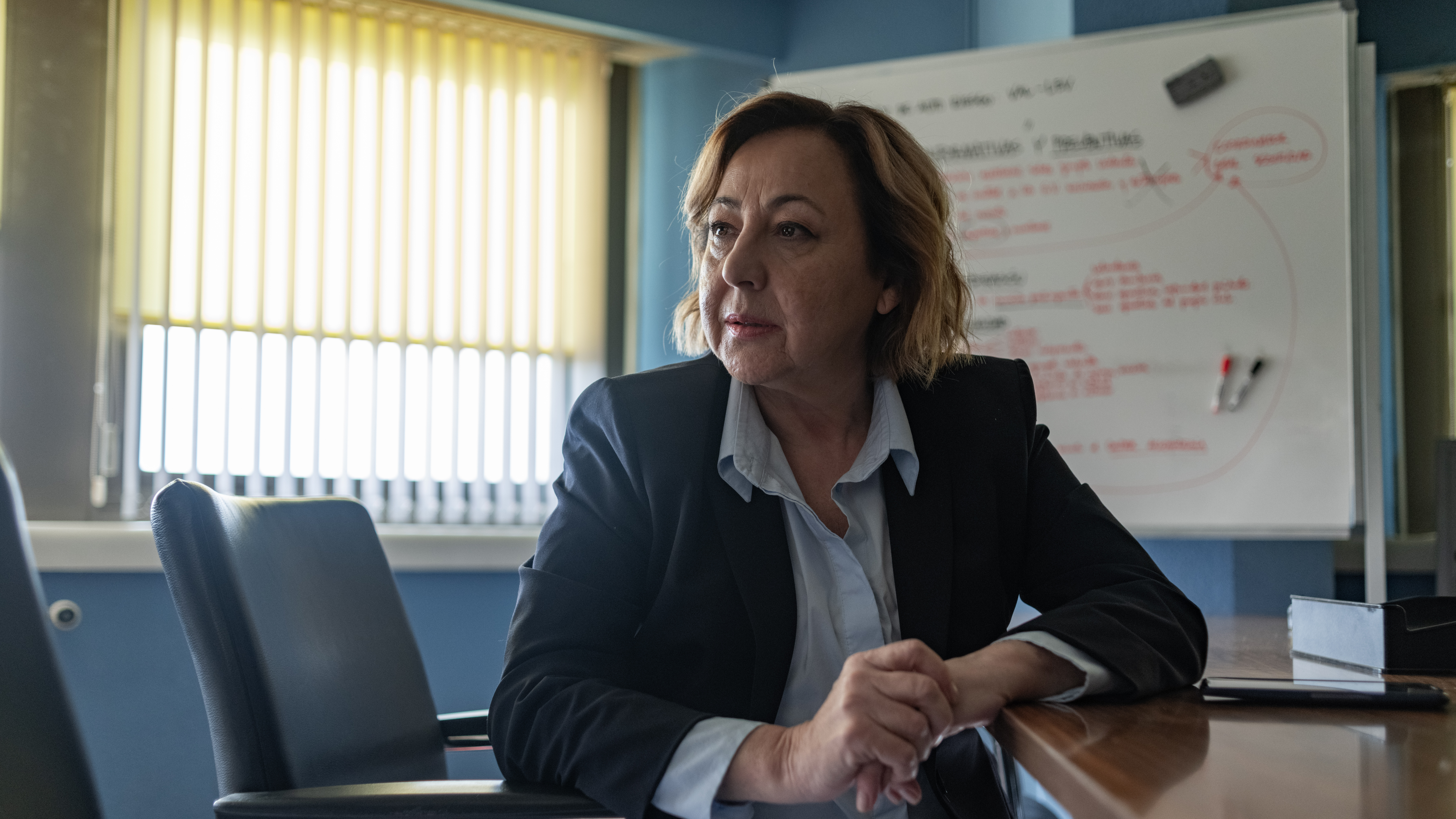 Carmen Machi in A Widow&#039;s Game, sitting in front of a whiteboard with case notes