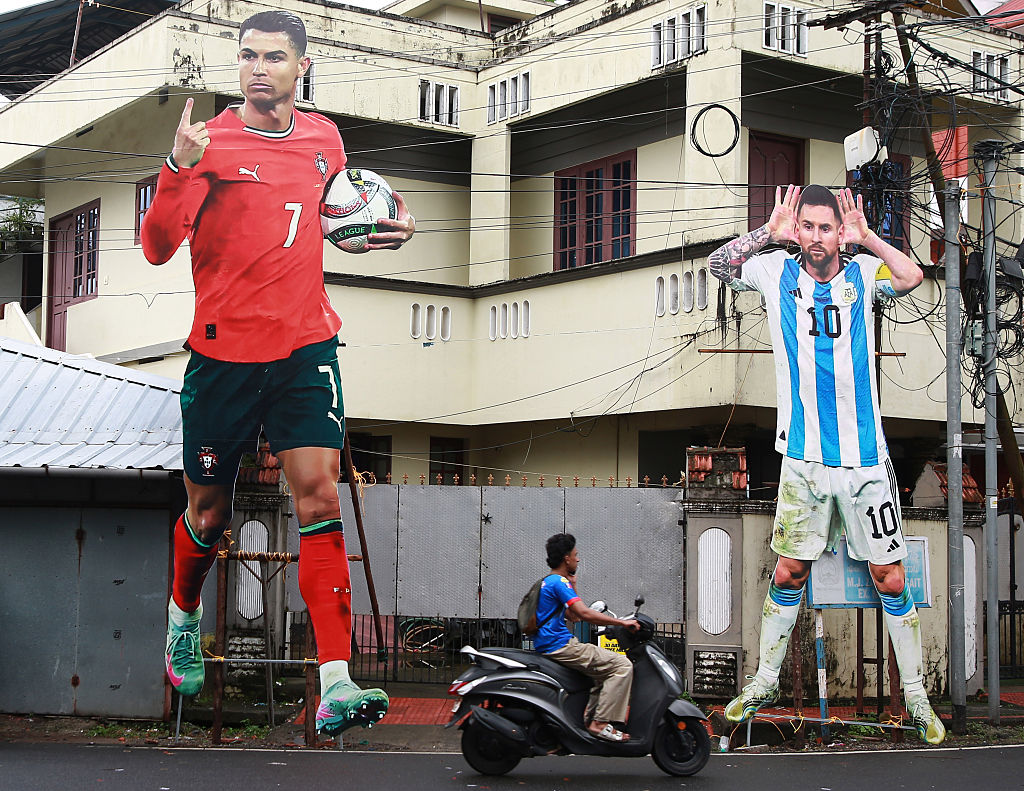 A man rides a scooter past giant cutouts of Portugal's Cristiano Ronaldo and Argentina's Lionel Messi displayed along a roadside in Kochi, India, on June 9, 2026, ahead of the 2026 FIFA World Cup