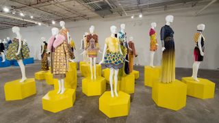 Highly patterned clothing on mannequins on yellow stands