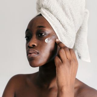 Woman applying a small amount of white cream to her face