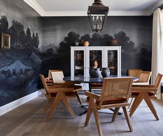 image of a dining room with a navy nature scene wall mural and a modern round table with scandi wooden chairs in the center of the room