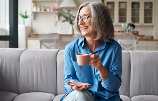 senior woman drinking a cup of tea on a sofa