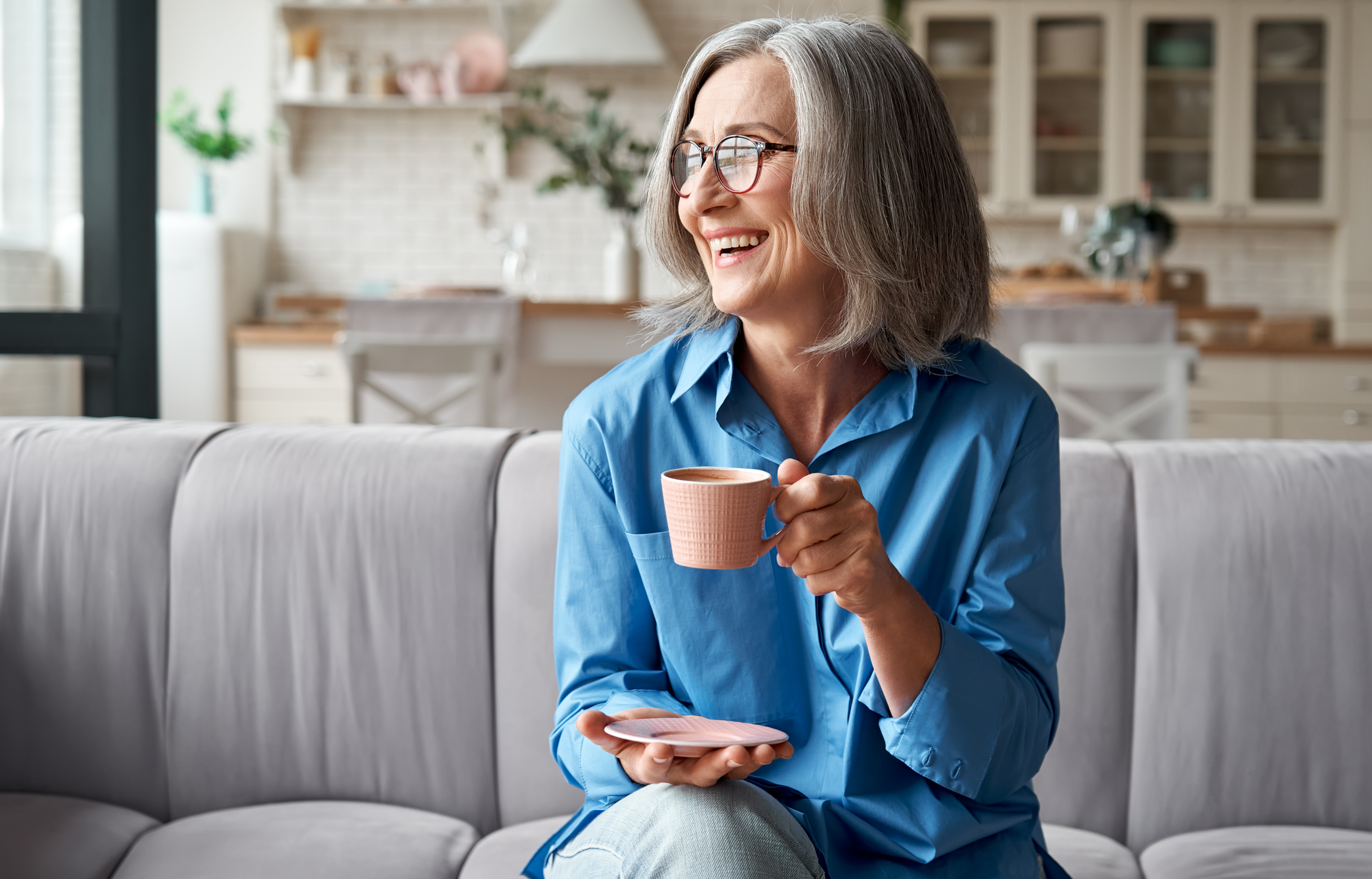 senior woman drinking a cup of tea on a sofa