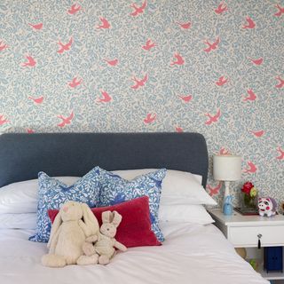 children's room with wallpaper and toys on bed