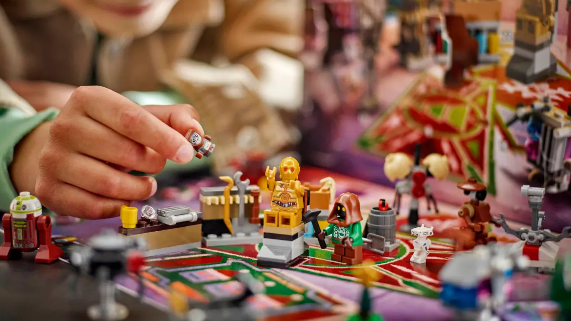 A hand places a Lego Babu Frik figure beside droids