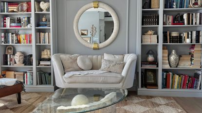 A BILLY bookcase on each side of a sofa in a living room space. A large mirror hangs above the sofa and opposite the sofa is a large glass coffee table