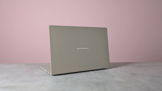 Rear three-quarter view of Asus Zenbook A16 open on desk with pink wall in background