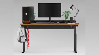 Herman Miller Coyl gaming desk with gaming PC, monitor, and lamp on top with backpack hanging on left hand side.