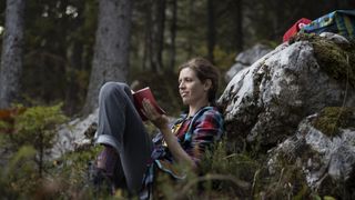 A hiker reading a book in the woods