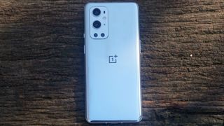 A OnePlus 9 Pro from the back, against a wooden surface