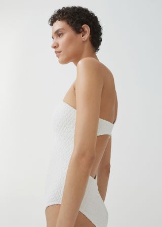 a model wearing a white asymmetrical patterned swimsuit