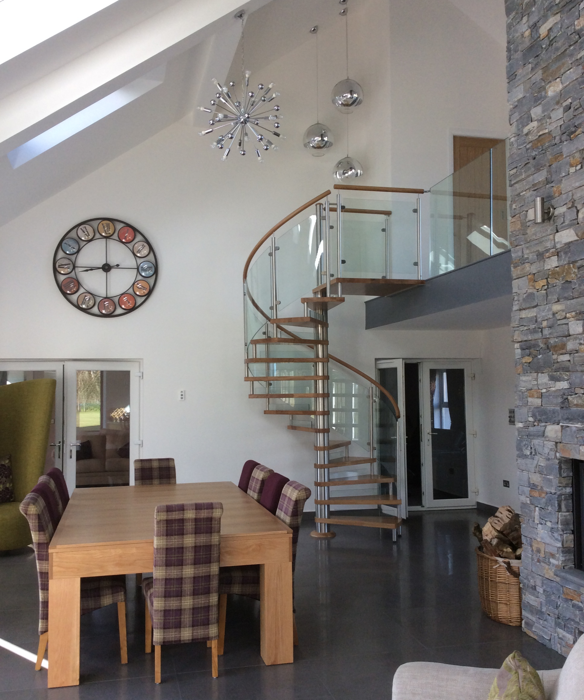 spiral wooden and glass staircase leading to mezzanine floor in contemporary home