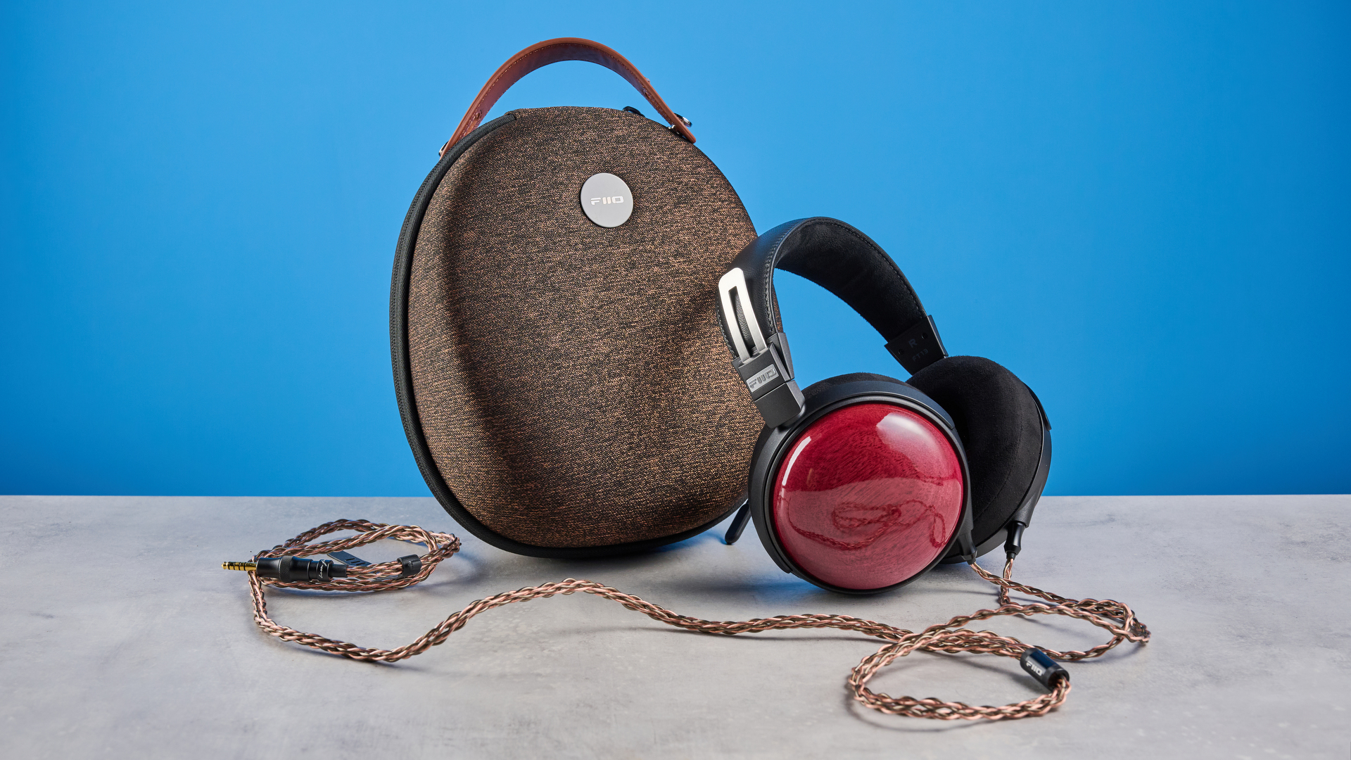 the fiio ft13 wired headphones with wood cups and copper cable photographed against a blue background