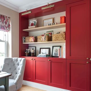 Red cabinetry with brass picture lights in home office