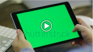 Hands holding a tablet with a green screen