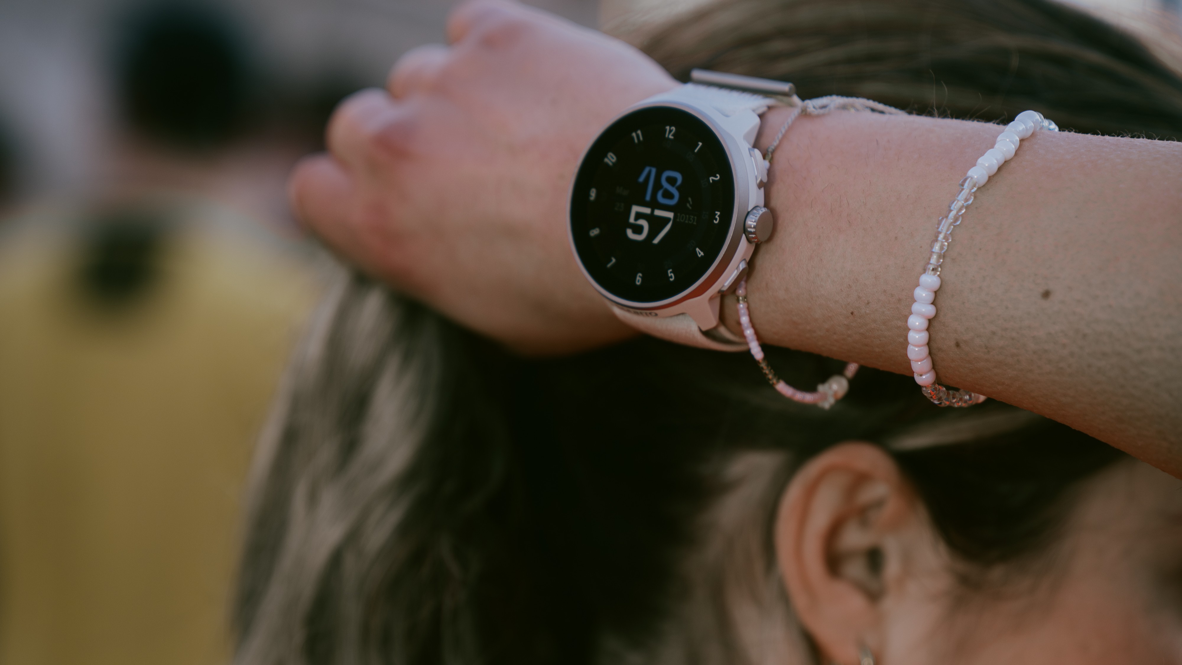 Close up of Suunto Run on runner's wrist as she adjusts her hair