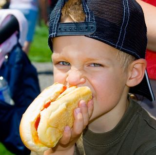 A boy eating a hot dog outdoors.