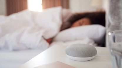woman in bed using white noise for sleep, machine in foreground