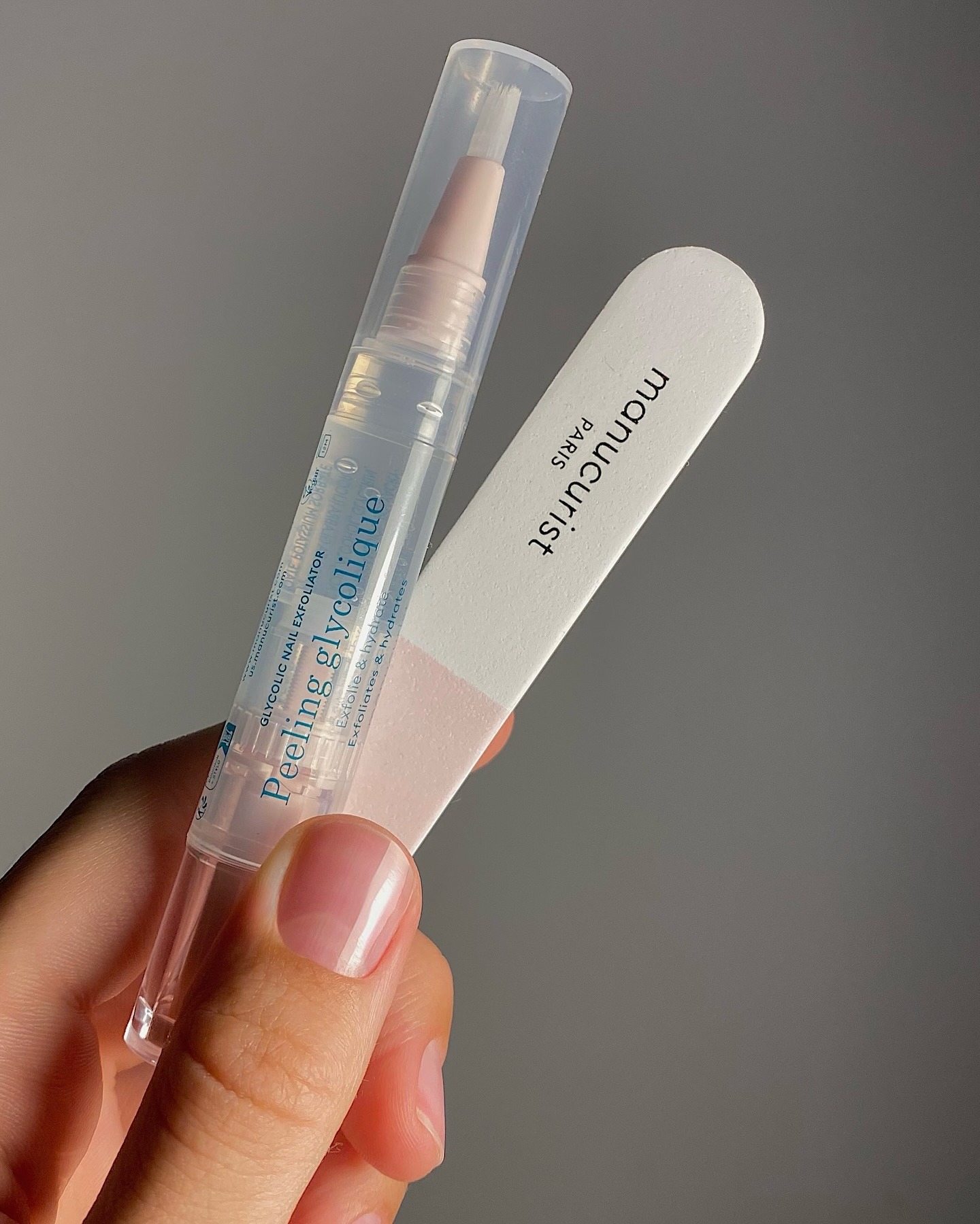 A Japanese manicure by @matejanova, holding nail serum and nail buffer in hand