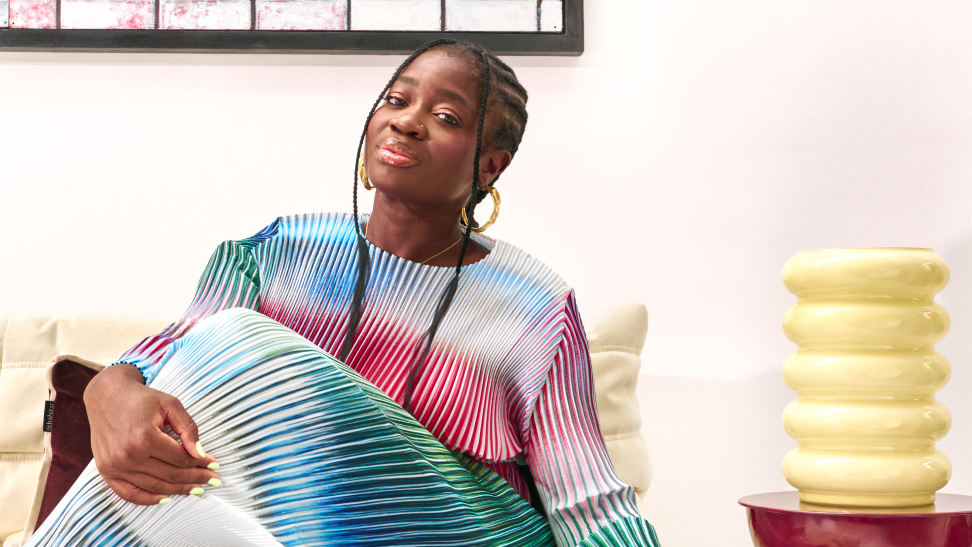 Clara Amfo in multi-coloured dress. There is a yellow vase next to her.