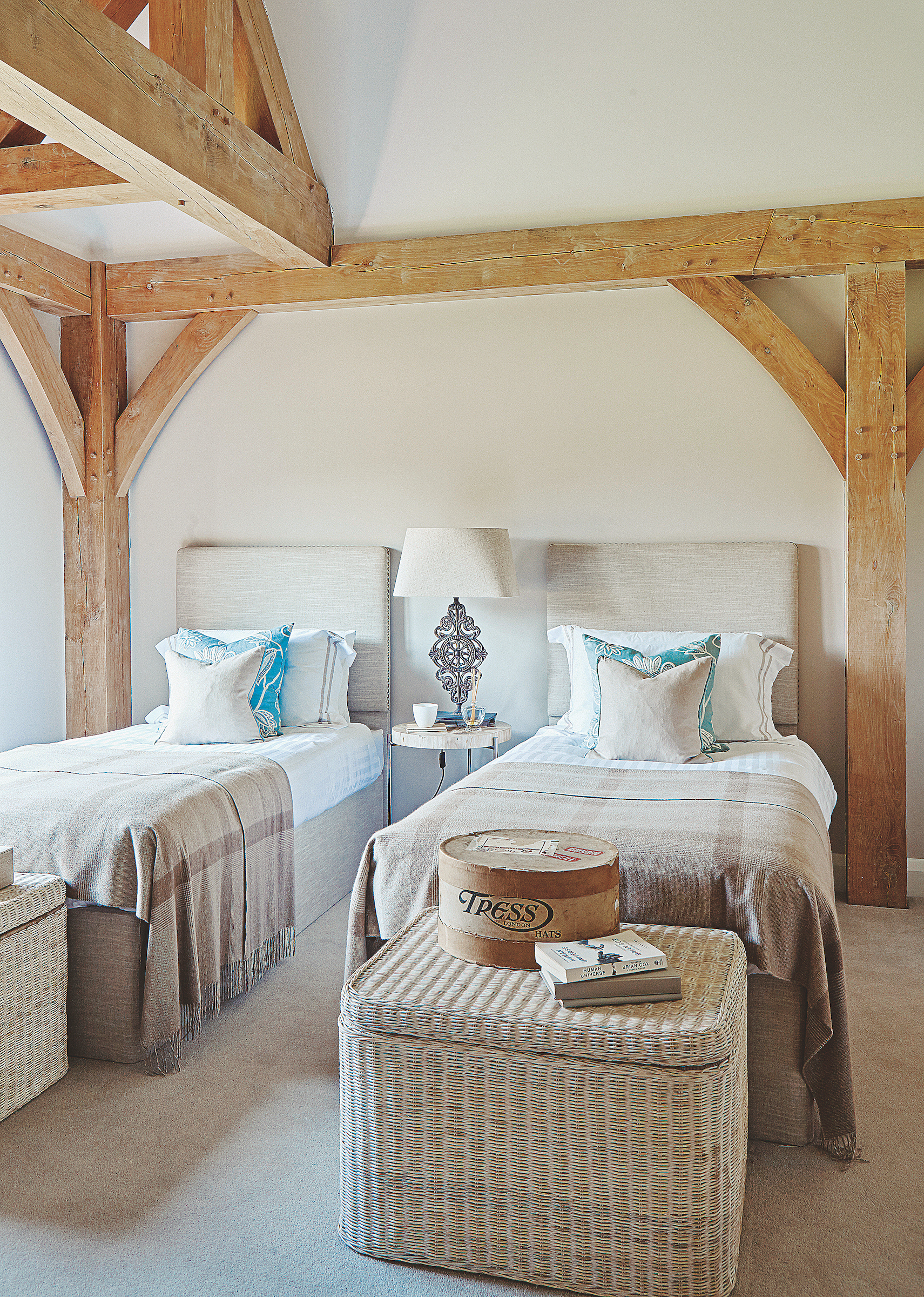 chambre à lits jumeaux avec poutres en bois et paniers en osier naturel