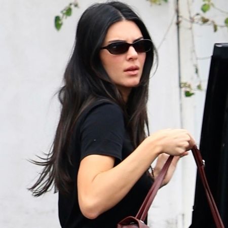 Kendall Jenner wore her white jeans outfit with the Chanel Maxi Flap Bag and matching burgundy ballet flats