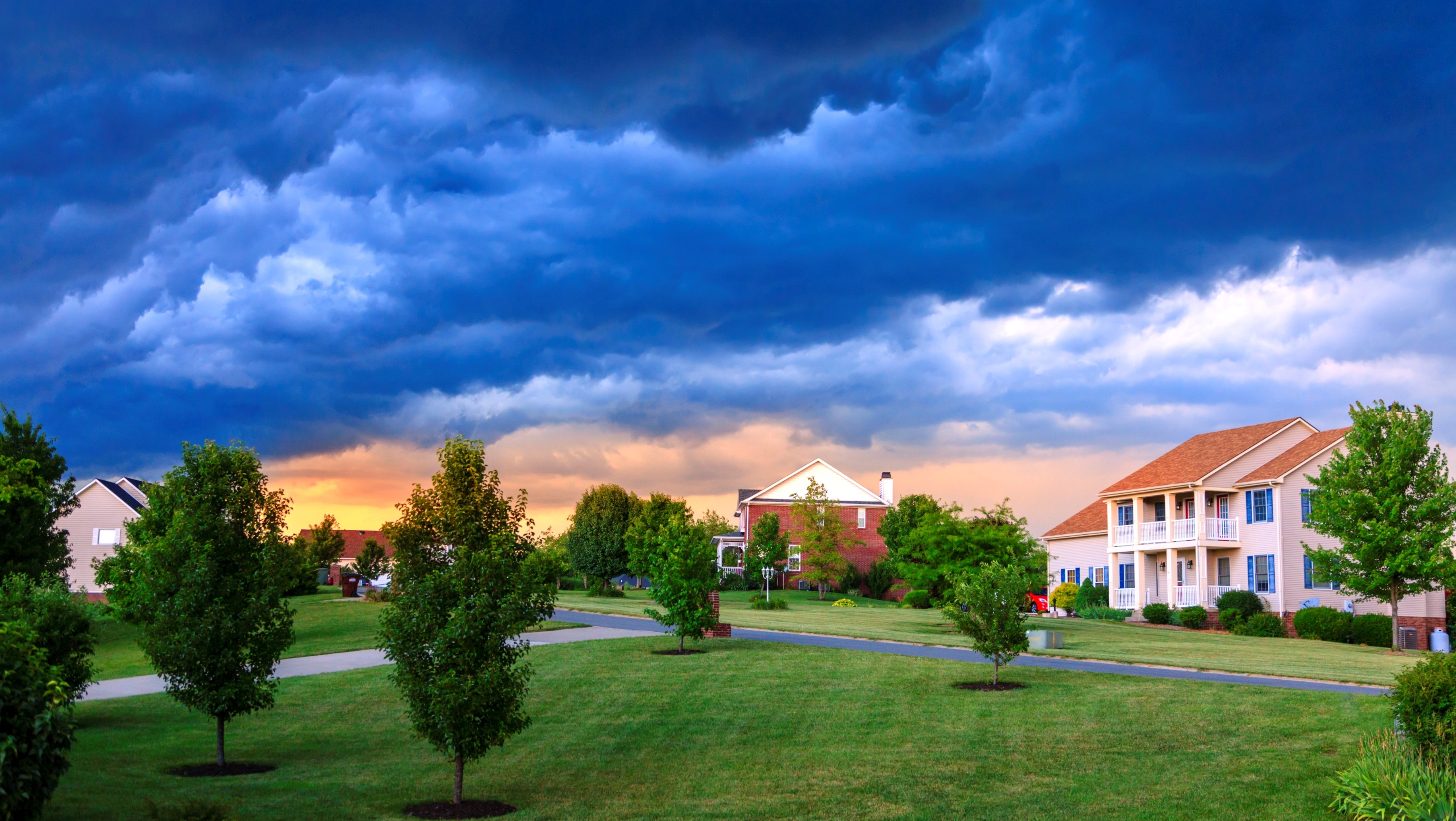 Storm clouds gather over a well-kept neighborhood.