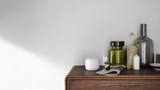 Google Nest WiFi router on dark wood sideboard next to green and blue decorative jars
