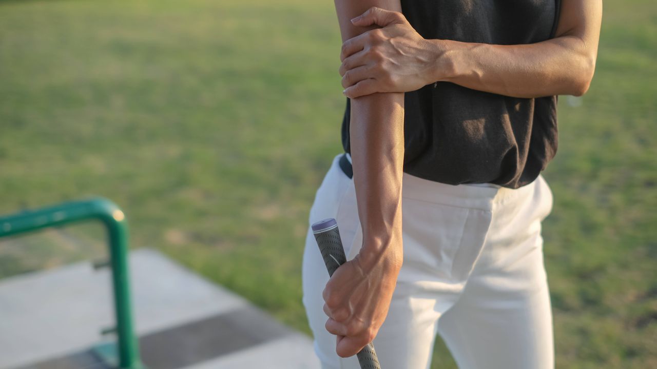 Woman golfer holding elbow