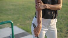 Woman golfer holding elbow