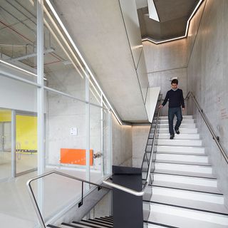 A male walking down a white stairwell.